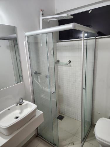 ein Bad mit einer Glasdusche und einem Waschbecken in der Unterkunft Rooftop 402: cobertura de um quarto no centro in Sete Lagoas