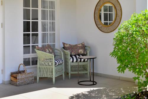a porch with two chairs and a table and a mirror at Fransvliet Guest House in Franschhoek