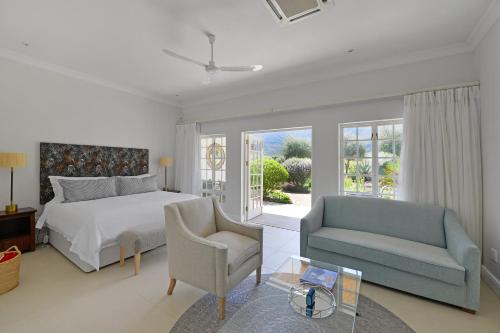 a bedroom with a bed and a couch and a chair at Fransvliet Guest House in Franschhoek