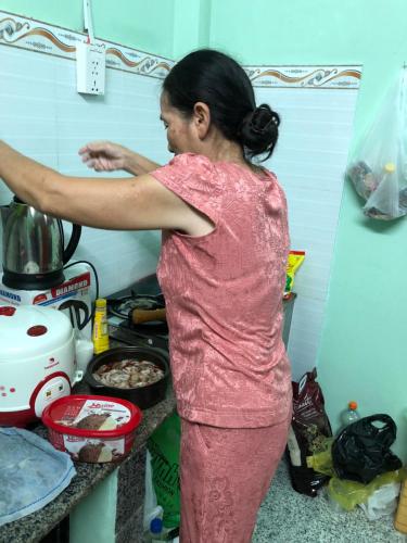 una mujer parada en una cocina preparando comida en sau khách sạn phong lan en Phan Rang