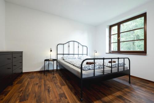 - une chambre avec un lit noir et une fenêtre dans l'établissement Apartmány Depandace Anička, à Deštné v Orlických horách