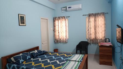 a bedroom with a bed with blue walls and curtains at Shantham Service Apartments, Indumanagar, Coimbatore in Coimbatore