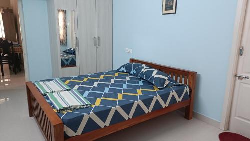 um quarto com uma cama com um edredão azul e amarelo em Shantham Service Apartments, Indumanagar, Coimbatore em Coimbatore