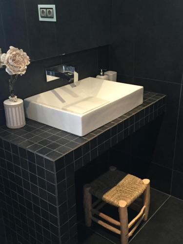 ein Badezimmer mit einem weißen Waschbecken und einem Stuhl in der Unterkunft Mas Pinoses in Les Llosses
