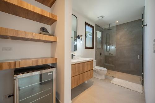 a bathroom with a shower and a toilet and a sink at Casa Cheetah Main House and Casita in Tamarindo