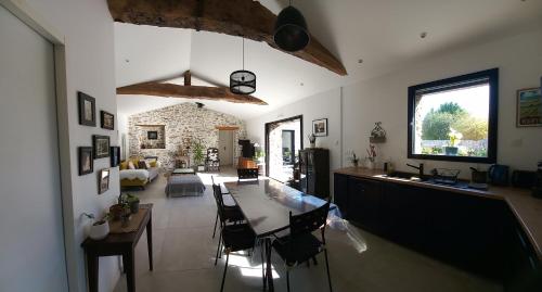 eine Küche und ein Wohnzimmer mit einem Tisch und Stühlen in der Unterkunft La villa du pressoir, classé 3 étoiles meublé de tourisme in Le Pallet