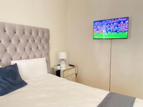 a bedroom with a bed and a flat screen tv on the wall at Siena Sun Guesthouse Rooms and Breakfast Option in Midrand