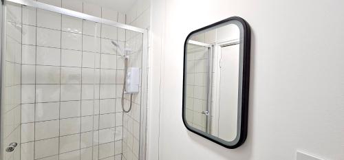 a mirror hanging on a wall in a bathroom at Harlequin Apartments by Switchback Stays in Cardiff