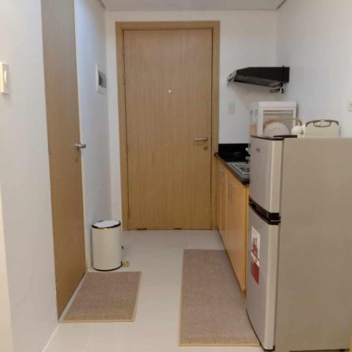 a kitchen with a refrigerator and a wooden door at GK's Condotel in Manila