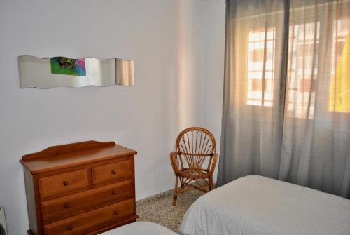 1 dormitorio con cama, silla y vestidor en Apartamento Benicasim 1ª línea de playa, en Benicàssim