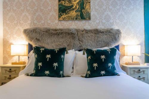 a bed with a large headboard with pillows and two lamps at Georgian House Garden Apartment in Bath