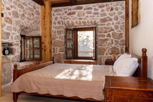 a bedroom with a bed and a stone wall at Old stone house with swimming pool Etno House Perazic in Bar