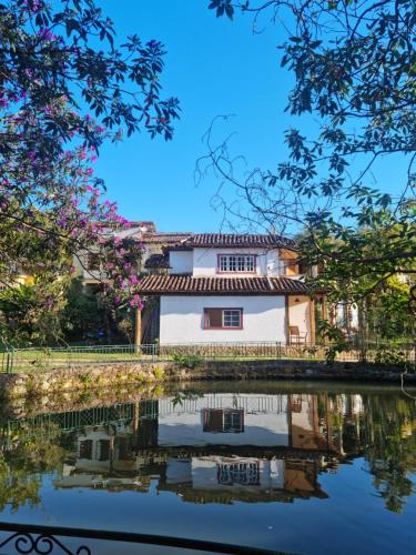 a house reflected in the water of a canal at Pousada Cipó Artes in Prados