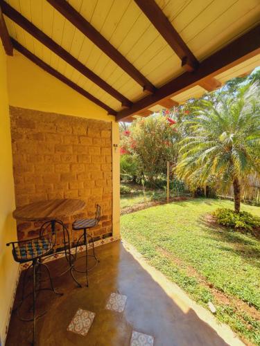 a patio with a table and chairs and a palm tree at Pousada Cipó Artes in Prados