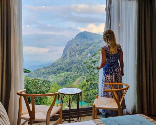 a woman looking out a window at a mountain view at HIDE ELLA Hotel & Resort in Ella