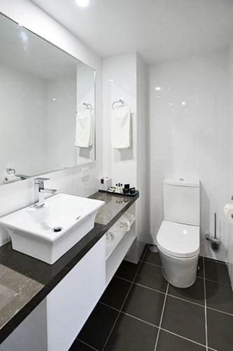 a white bathroom with a sink and a toilet at Astro Dish Motor Inn in Parkes