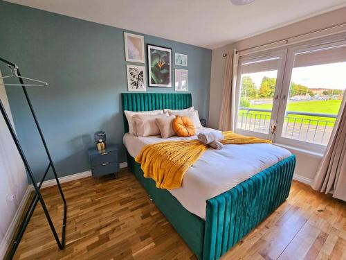 een slaapkamer met een groot bed met een groen hoofdeinde bij Modern 5 Bedroom Townhouse with Free Parking in Glasgow