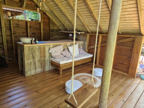 a porch of a wooden cabin with a swing at PURA VIDA Lodge Cabane perchée in Sainte-Rose
