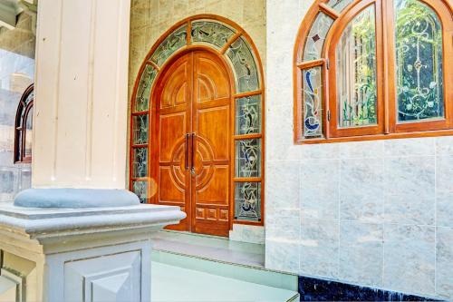 een houten deur in een kamer met 2 ramen bij SPOT ON 93144 Homestay H. Syarif Syariah - Bandar Gresik 2 in Gresik