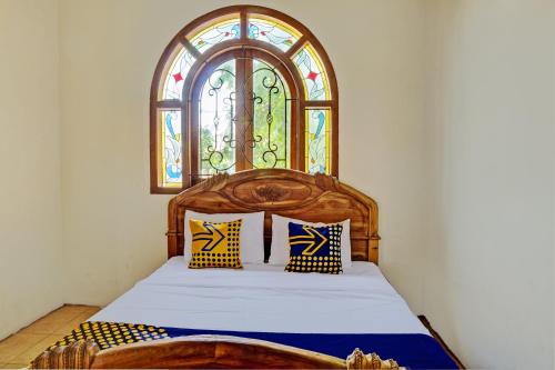 een slaapkamer met een houten bed en een glas-in-loodraam bij SPOT ON 93144 Homestay H. Syarif Syariah - Bandar Gresik 2 in Gresik