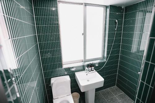 a green tiled bathroom with a sink and a toilet at Stay Ccassette Player in Mokpo