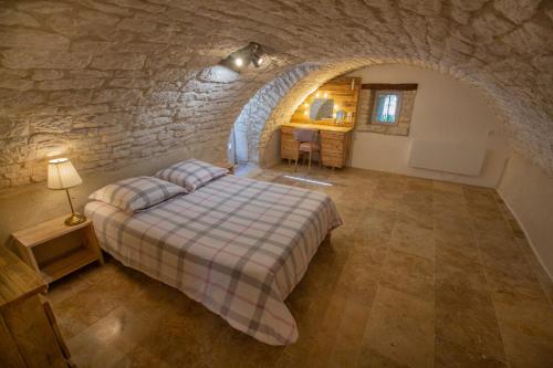 sypialnia z łóżkiem w kamiennej ścianie w obiekcie Maisonnette Lotoise, meublé de tourisme 3 étoiles w mieście Fargues