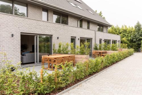 a patio with a table and benches in front of a building at Abalona Hotel & Apartments in Dendermonde