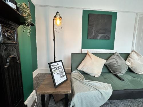 a living room with a green couch and a table at 78 Victoria Road in Liverpool