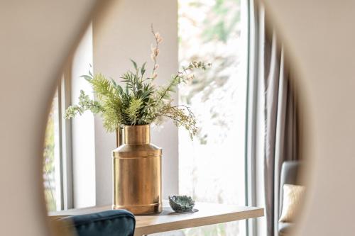 a vase with flowers sitting on a table next to a window at Abalona Hotel & Apartments in Dendermonde