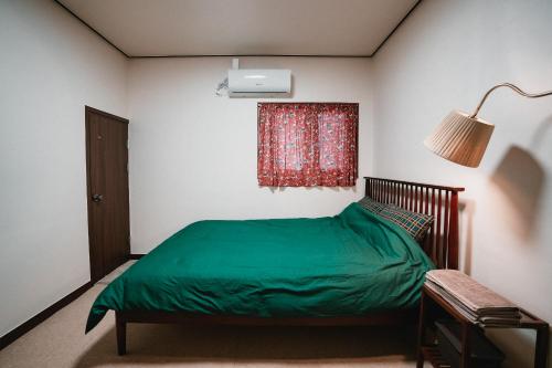 a bedroom with a green bed and a window at Stay Ccassette Player in Mokpo