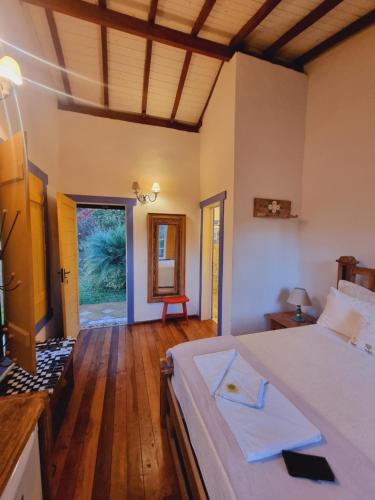 a bedroom with a large bed and a wooden floor at Pousada Cipó Artes in Prados