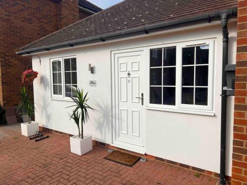 a white garage with a door and a potted plant at Minster Hilltop Apartment in Minster