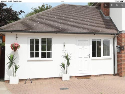 a white garage with two potted plants in front of it at Minster Hilltop Apartment in Minster