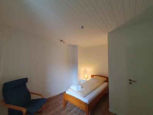 a bedroom with a bed and a blue chair at Privatzimmer im Schlesischen Viertel - nahe Uniklinik in Mainz