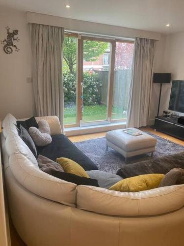 a living room with a white couch in front of a window at Lovely and spacious Wimbledon Flat in London