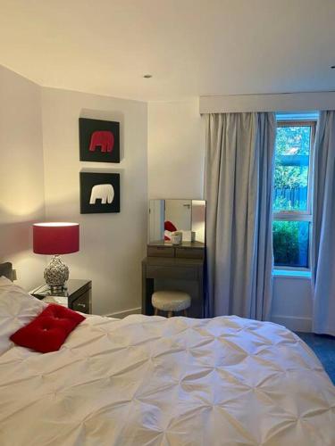 a bedroom with a bed and a desk and a window at Lovely and spacious Wimbledon Flat in London