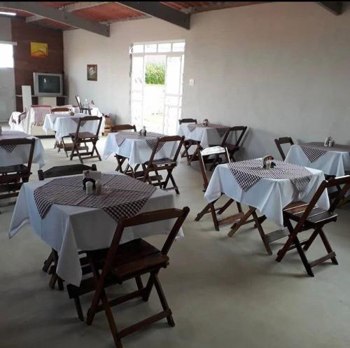 a room with tables and chairs with white tablecloths at Pousada Sabia Capitolio in Capitólio