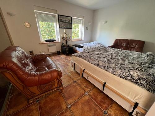 a bedroom with a bed and two leather chairs at Apartament Zloty Pociag in Wałbrzych