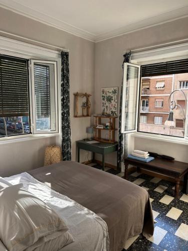 a bedroom with a bed and a desk and two windows at Room Pilar in Rome