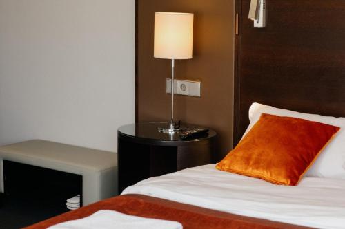a bedroom with a bed and a lamp on a table at Excelsior INN in Turda