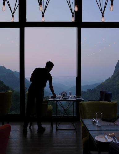 a man standing at a table in a room with windows at HIDE ELLA Hotel & Resort in Ella
