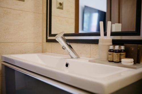 a bathroom sink with a faucet and a mirror at Excelsior INN in Turda