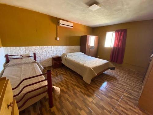 een slaapkamer met twee bedden en een houten vloer bij Casa en pinar del norte san luis in Barranca Colorada