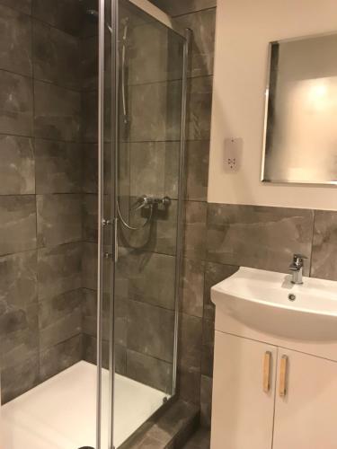 a shower with a glass door next to a sink at Redhill Lodge in Farnham