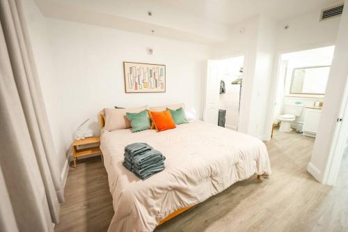 a white bedroom with a bed with orange and green pillows at Apt Orlando 11th Floor 5 min from Disney in Orlando