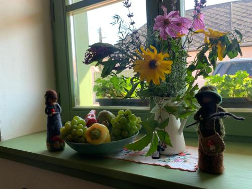 a window sill with a bowl of fruit and a vase with flowers at Pannonhalma Várlak Vendégház in Pannonhalma