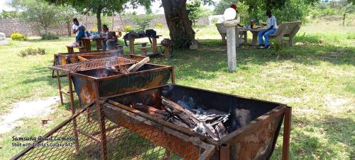 una parrilla de barbacoa en un campo con gente sentada en una mesa en Khutsong Lodge, en Acornhoek