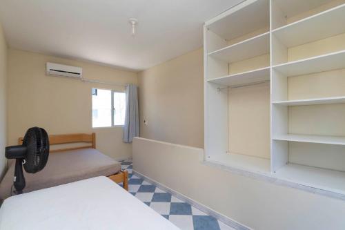 Cette chambre comprend un lit, une fenêtre et des étagères. dans l'établissement Residencial Melfi 2, à Bombinhas