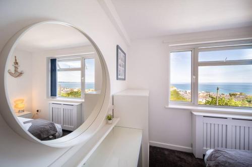 um espelho num quarto branco com uma cama e duas janelas em Newquay Sunset & Sea View Apartment in Town Centre em Newquay