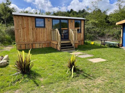 a wooden cabin with a bench in a yard at Pembrokeshire Shepherd hut with hottub in Jordanston